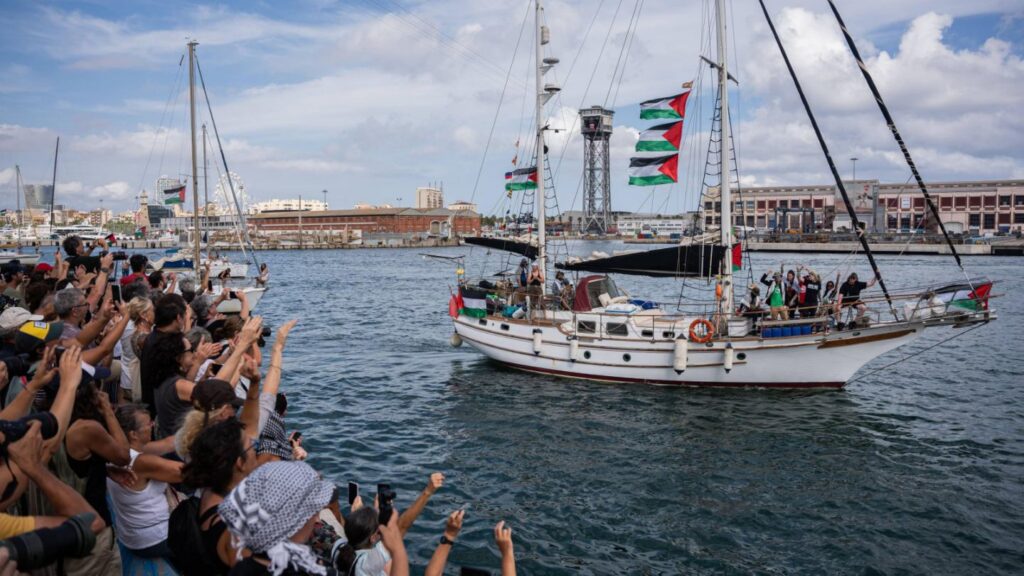 A ship of the Global Sumud Flotilla departing from harbour, as supporters on the dock cheer on and greet it.